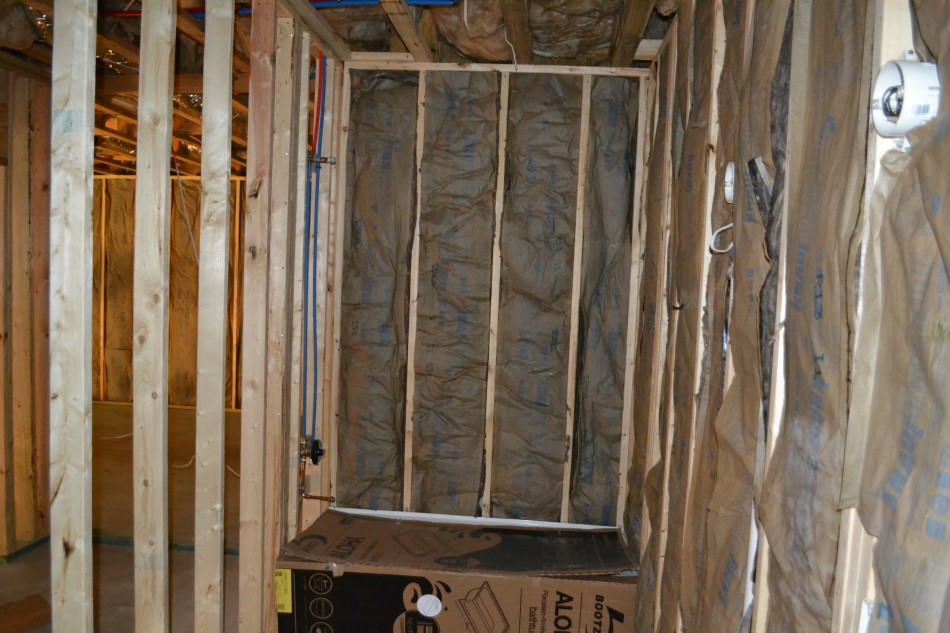 Basement bedroom under construction with stud framing, insulation and plumbing rough-in before drywall